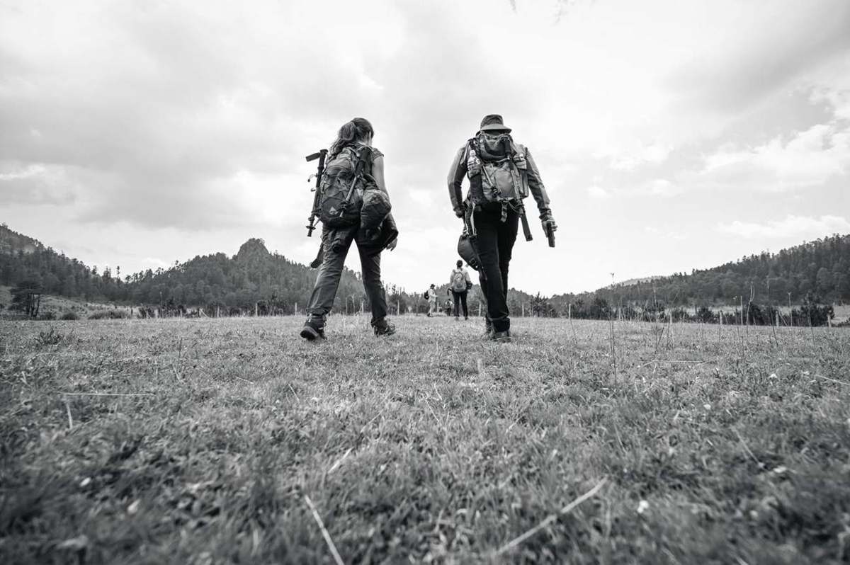 Dos personas caminando por un pastizal de montaña