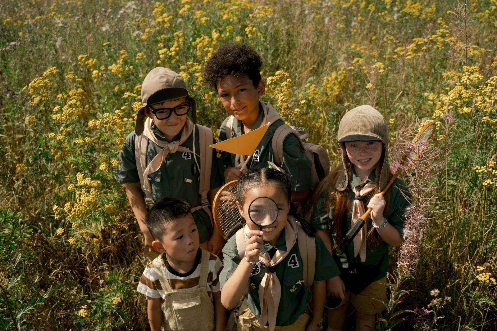 Niñas y niños exploradores observando el bosque con una lupa